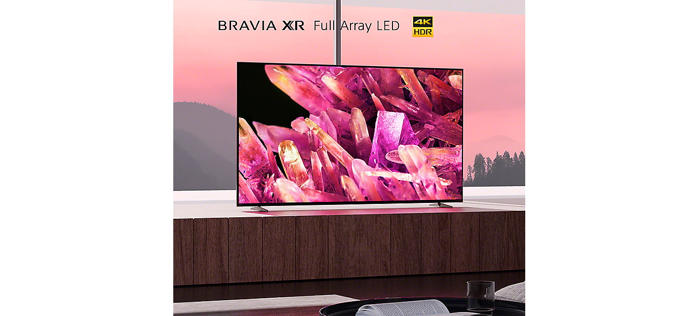 BRAVIA X90K on wooden platform in living room with image of pink crystals on screen