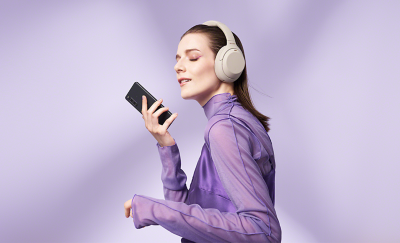 A woman wearing headphones and holding an Xperia 10 IV