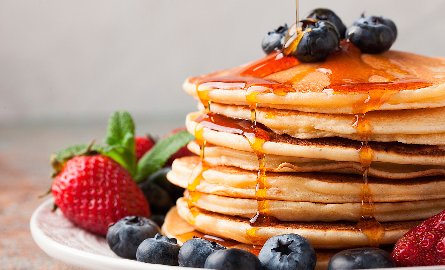 A stack of pancakes topped with berries and maple syrup