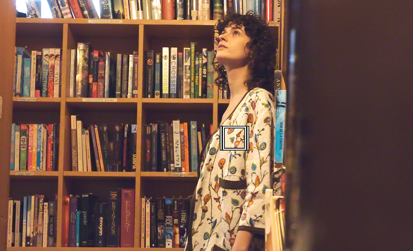 Una mujer explorando una biblioteca. El cuadrado blanco denota el rastreo de objetos para vídeo