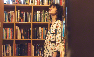 一位女士正在圖書館隨處看看，白色方格表示影片的物件追蹤功能