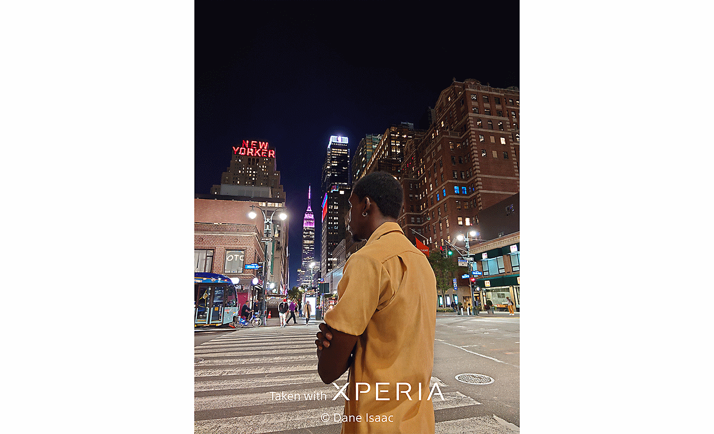 Večerný záber na mestské ulice s mužom v popredí. Na fotografii sa nachádza text Taken with XPERIA ©Dane Isaac.