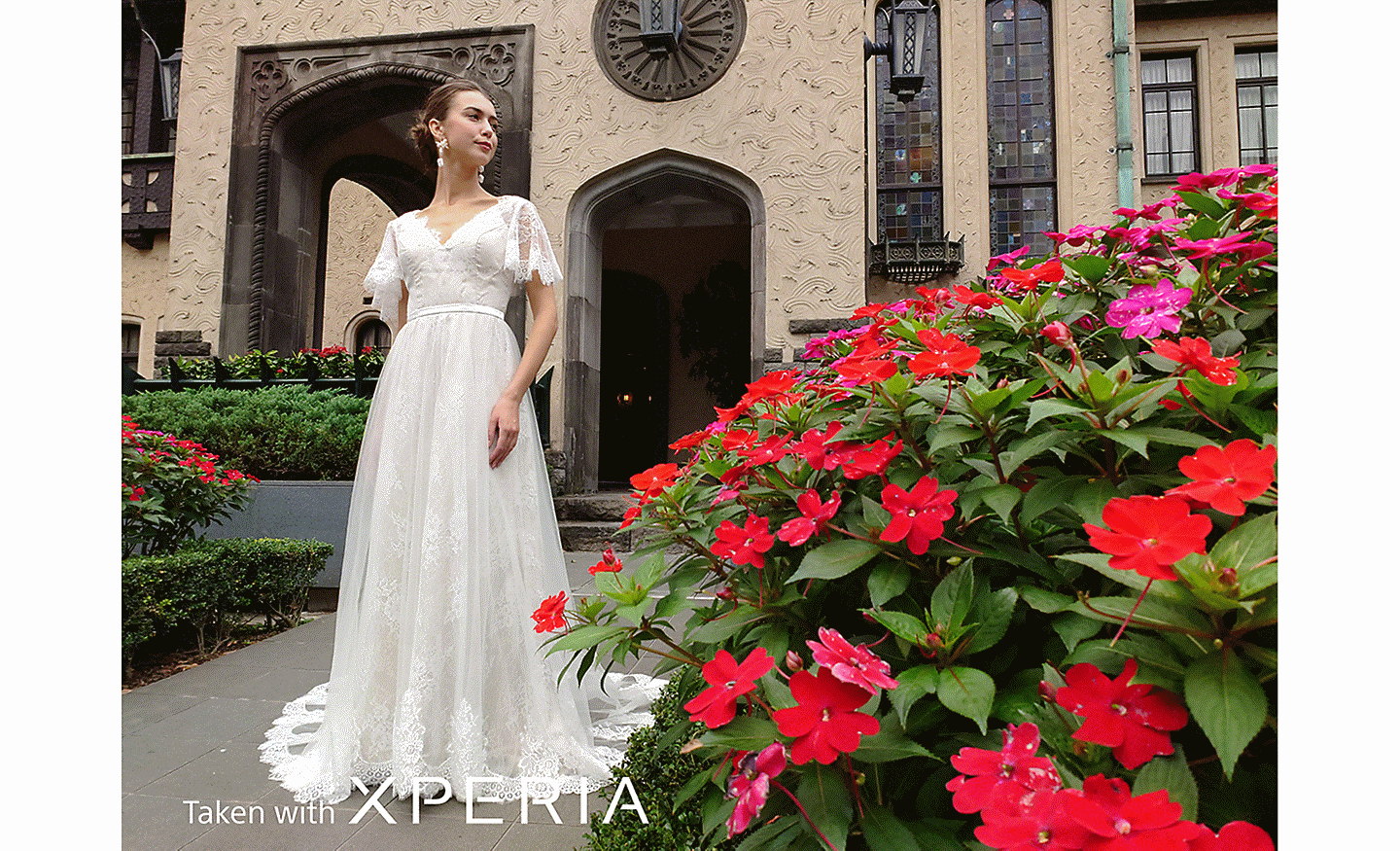 A bride posing outside a building with red flowers in the foreground. Text reads "Taken with XPERIA".