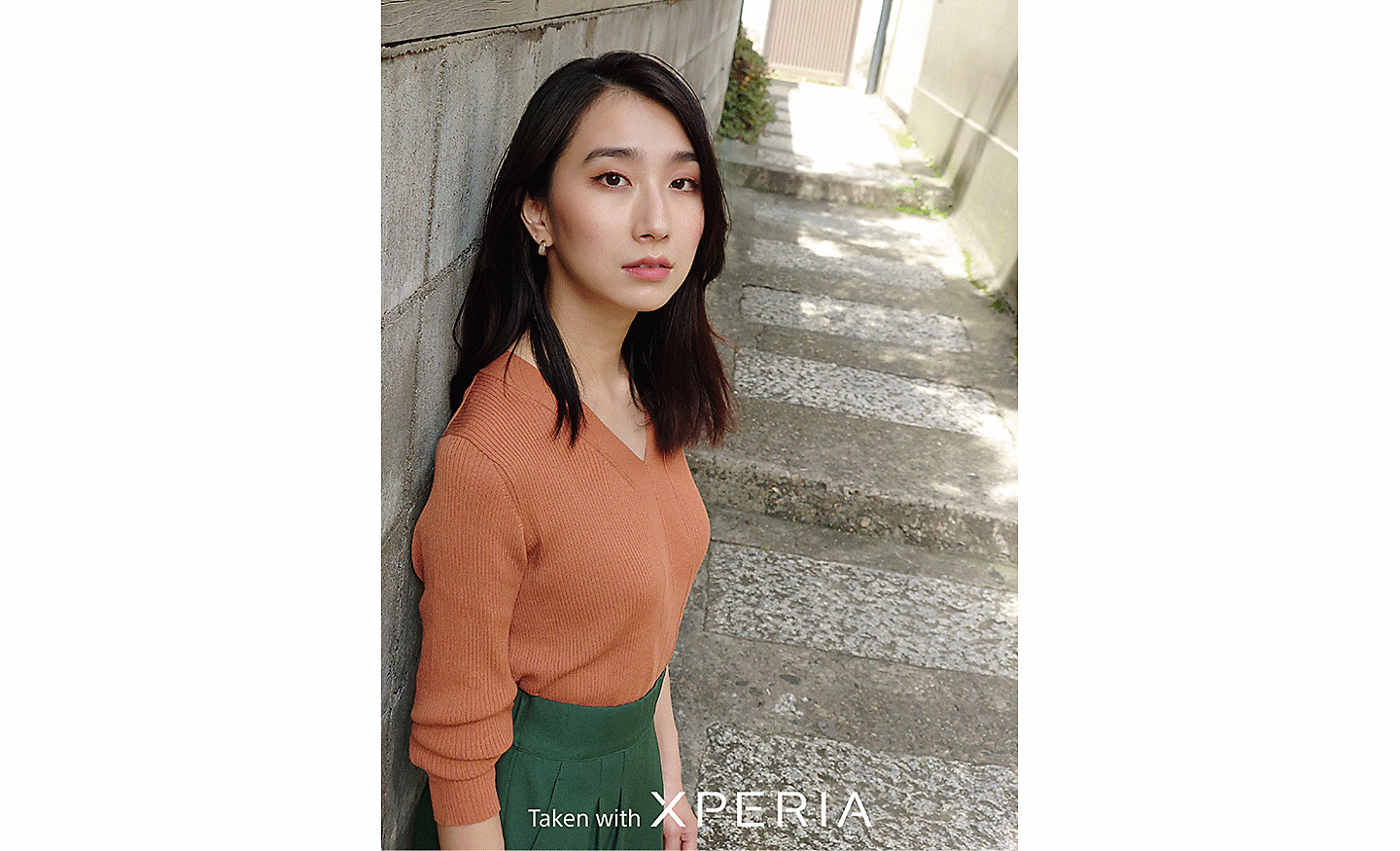 Portrait of a woman on some stone steps. Text reads "Taken with XPERIA".