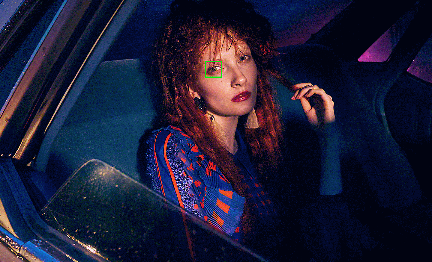 Snímek ženy v autě pořízený za slabého osvětlení se zeleným bodem automatického ostření překrývajícím její oko