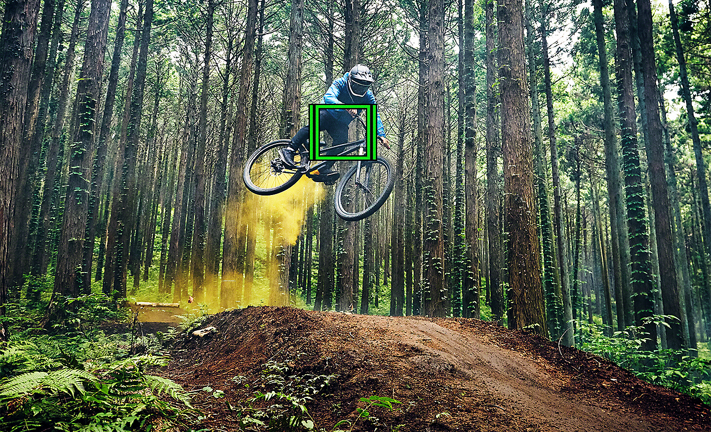Mountain biker jumping in a forest with green square indicating Real-time Tracking