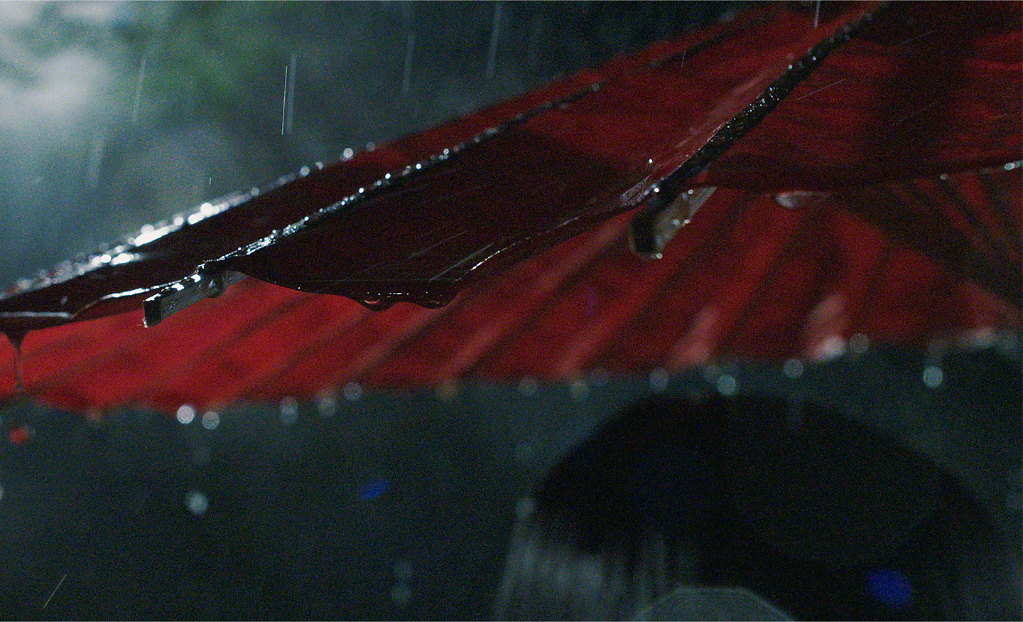 Auf einen roten Sonnenschirm fallender Regen