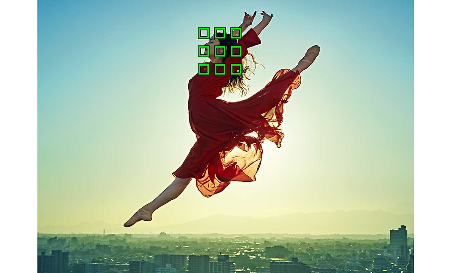 Danseuse en robe rouge en train de sauter devant un grand paysage urbain, 9 carrés verts regroupés représentant la détection de sujet basée sur l'IA