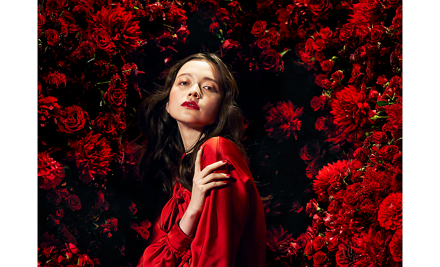 Bild på kvinna i rött omgiven av röda blommor, tagen med 125 mm-objektiv