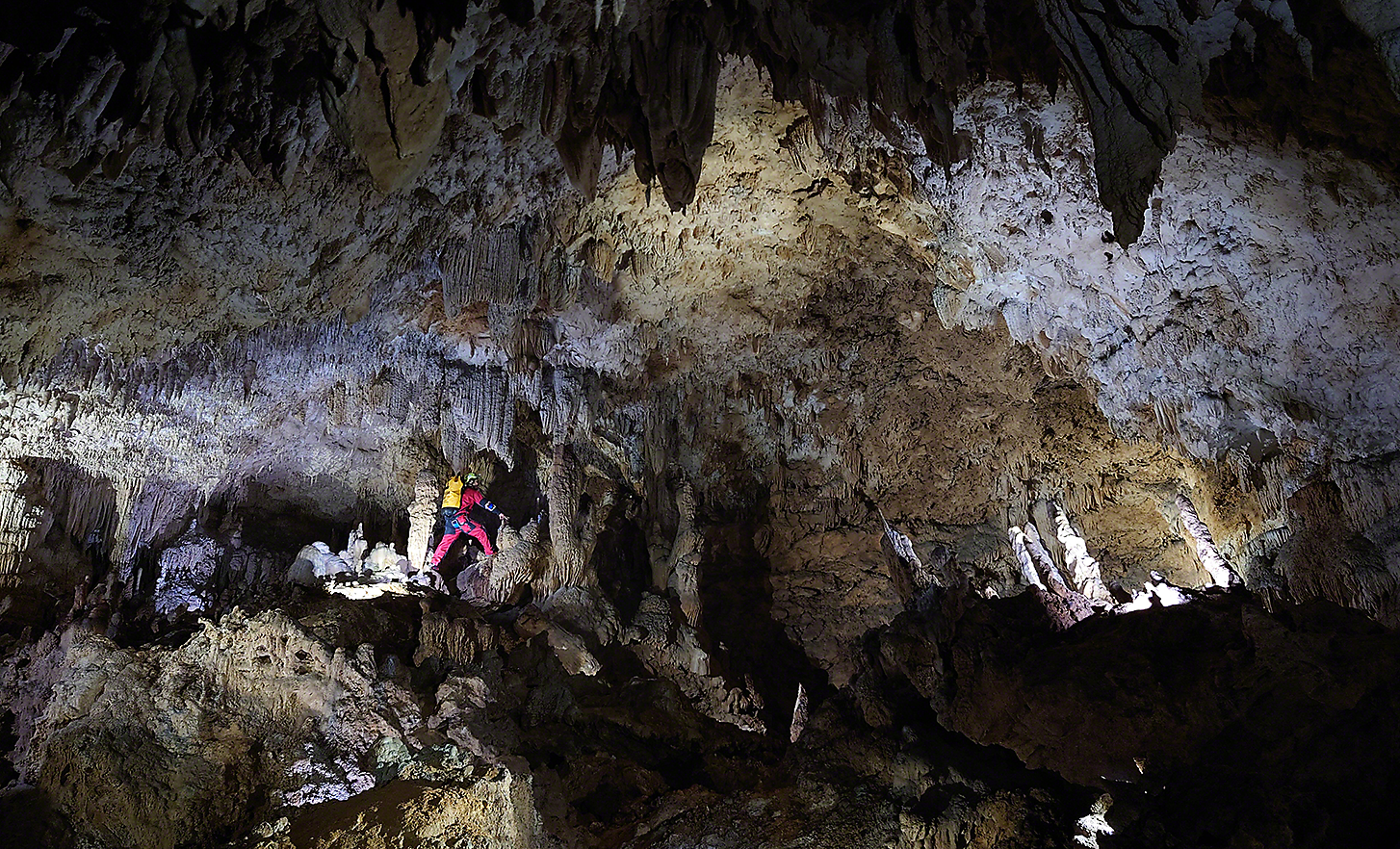 En bild i svagt ljus av en grottforskare som utforskar en stor grotta
