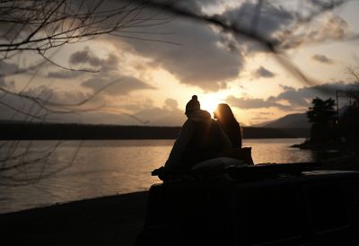 Image of two people sitting close to each other, with an evening scene in background
