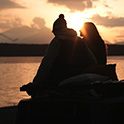 Image of two people sitting close to each other, with an evening scene in background