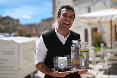 Image of a man carrying a tray of drinks with a smile in PT (Portrait) mode.