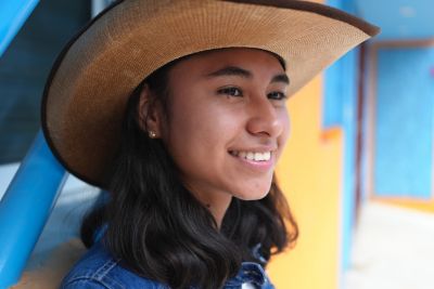 Image of a woman with a hat smiling in PT (Portrait) mode.