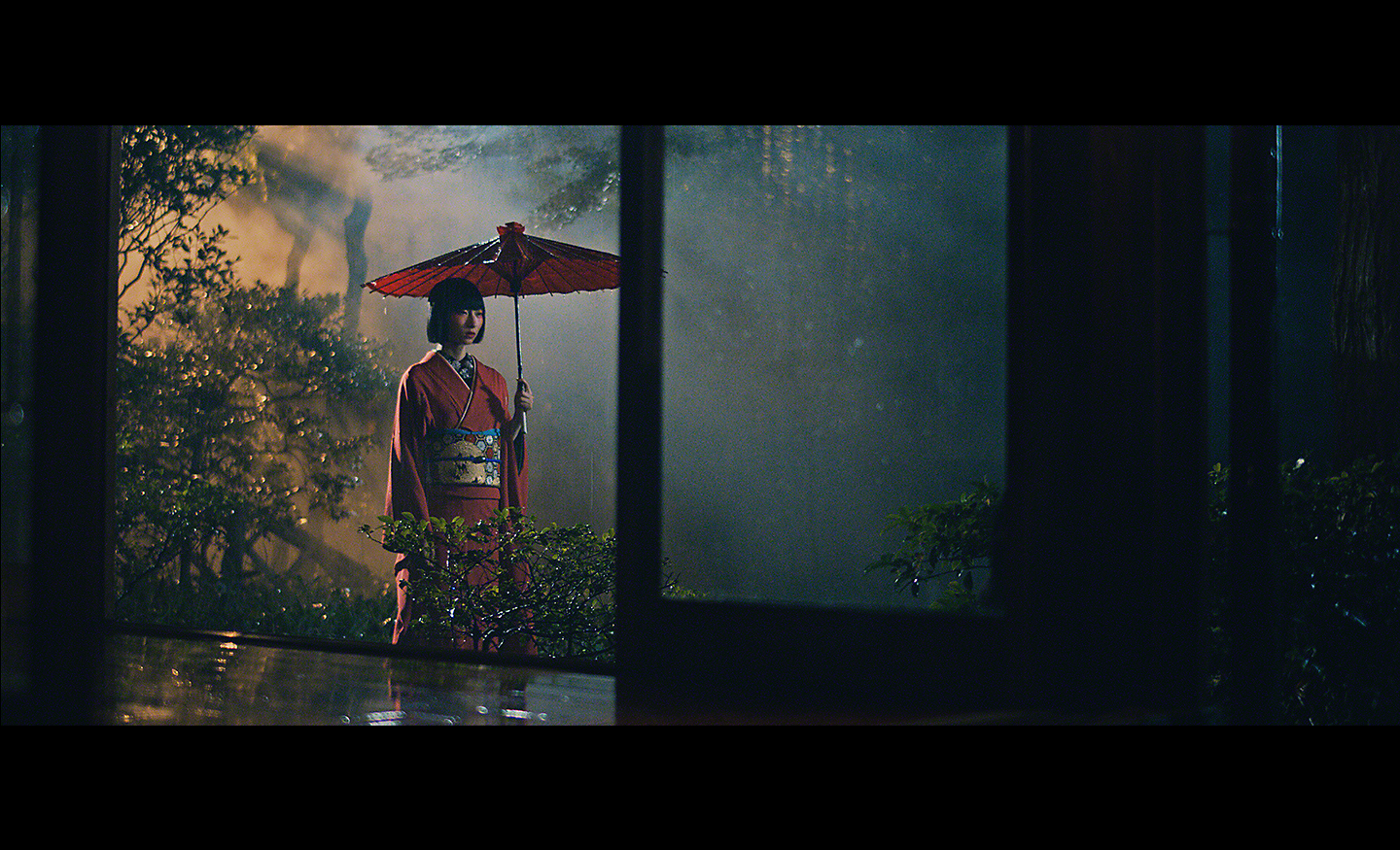 Hình ảnh trong ánh sáng yếu chụp người phụ nữ cầm chiếc ô che nắng màu đỏ
