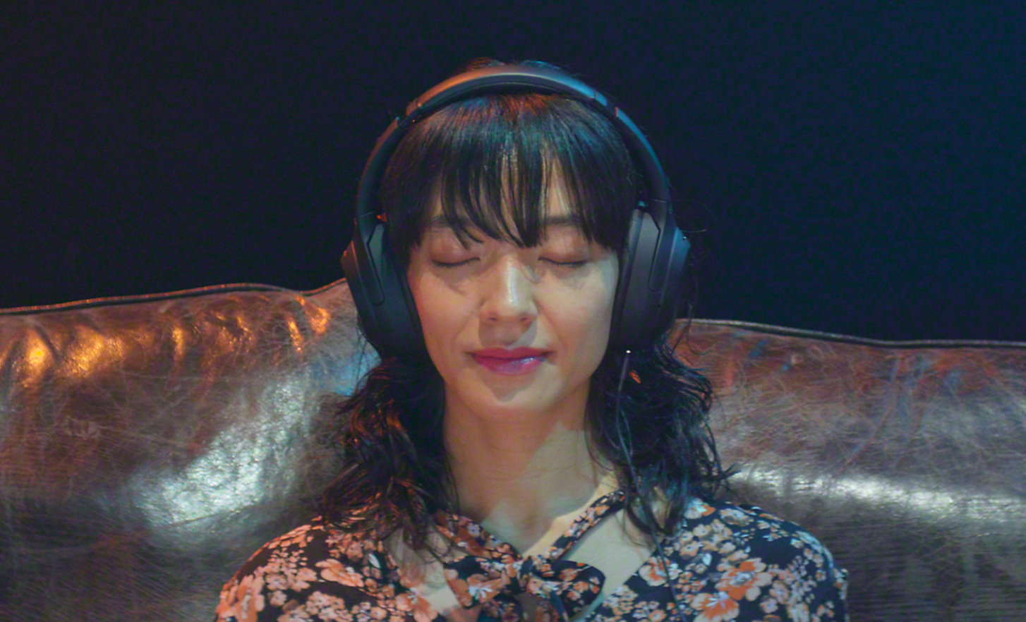 Una mujer escuchando música por los auriculares con los ojos cerrados