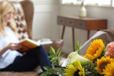 Imagen de flores enfocadas con una mujer en el fondo borroso