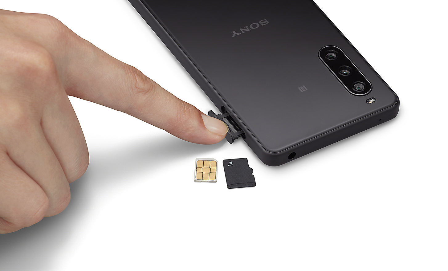 Close-up van iemand die zijn vinger gebruikt om toegang te krijgen tot de SIM-lade op de Xperia 10 IV, plus een SIM-kaart en een SD-kaart