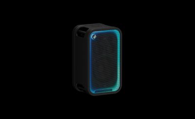 Una imagen de producto en estudio de tres cuartos que muestra el parlante para fiestas ULT TOWER 7 de Sony negro en posición vertical sobre un fondo claro y liso. La rejilla de malla frontal está enmarcada por una brillante tira de luces LED que pasa de cian en la parte superior a azul oscuro y morado en la parte inferior. El botón circular "ULT" ilumina la esquina superior izquierda y las asas de transporte incorporadas están integradas en los bordes superior e inferior del panel lateral.