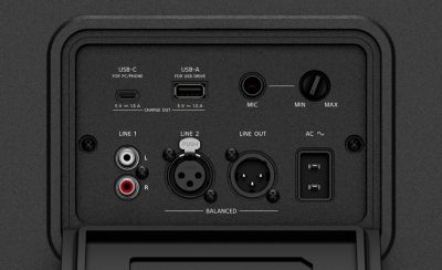 Imagen en estudio en primer plano de la entrada negra posterior y del panel de control del parlante ULT TOWER 5. El panel cuenta con un compartimento de entradas empotrado ubicado debajo de una pequeña luz blanca, que incluye puertos físicos USB-C, USB-A, un conector "MIC" con una perilla de volumen, entradas RCA "LINE 1" y puertos XLR balanceados "LINE 2" y "LINE OUT" situados sobre una cubierta rectangular plegable de protección.