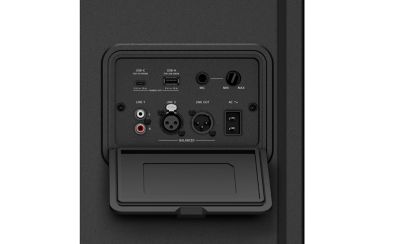 Imagen en estudio en primer plano de la entrada negra posterior y del panel de control del parlante ULT TOWER 7. El panel cuenta con un compartimento de entradas empotrado ubicado debajo de una pequeña luz blanca, que incluye puertos físicos USB-C, USB-A, un conector "MIC" con una perilla de volumen, entradas RCA "LINE 1" y puertos XLR balanceados "LINE 2" y "LINE OUT" situados sobre una cubierta rectangular plegable de protección.
