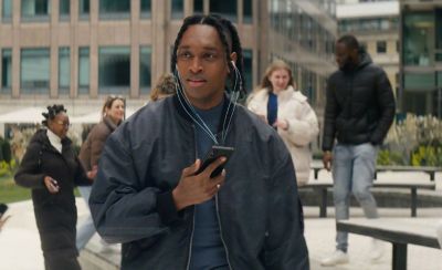 A person listens to a pair of Sony in-ear headphones whilst holding an Xperia phone, white lines run between the two