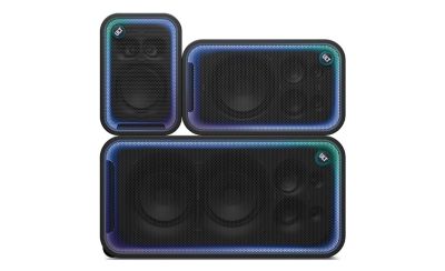 Una imagen de producto en estudio que muestra tres parlantes ULT TOWER MAX de Sony negros apilados sobre un fondo blanco liso. En la parte inferior se encuentra el parlante más grande, colocado en posición horizontal. Encima de él están los otros dos: uno a la izquierda en posición vertical, mientras que el de la derecha está en posición horizontal. Los tres parlantes cuentan con rejillas de malla negras cuyos contornos están delineados por tiras de luces LED brillantes que pasan por tonos cian, azul y morado, y cada uno tiene un prominente botón circular "ULT" en la cara frontal.