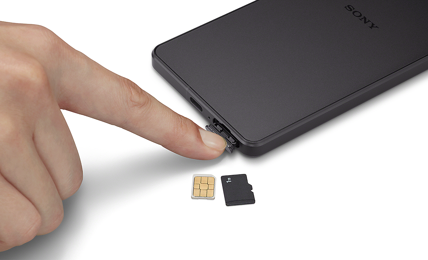 Primo piano di qualcuno che usa il dito per accedere al vano SIM di Xperia 1 IV, più una scheda SIM e una scheda SD