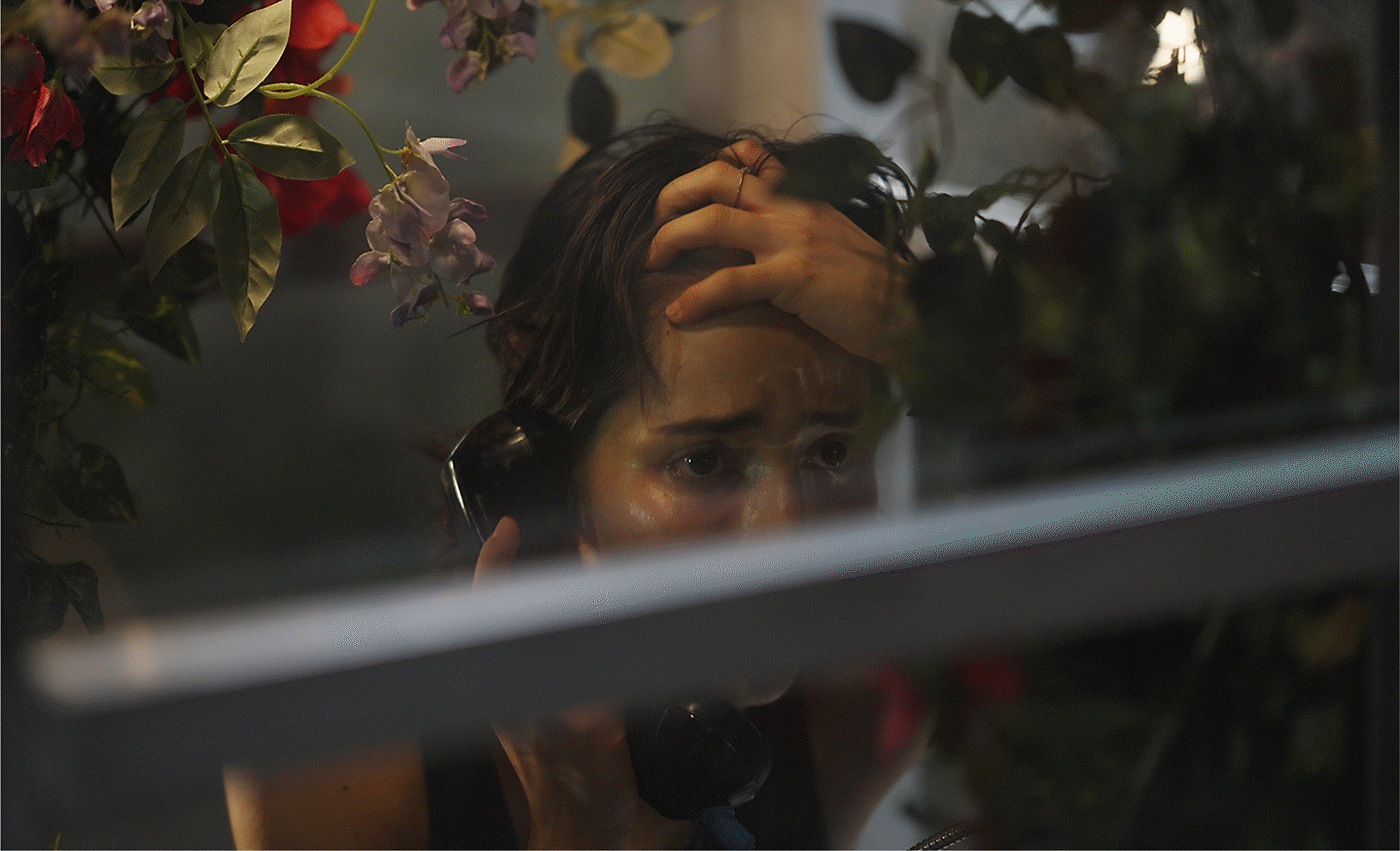 Egy ablakon keresztül készült kép egy telefonáló nőről