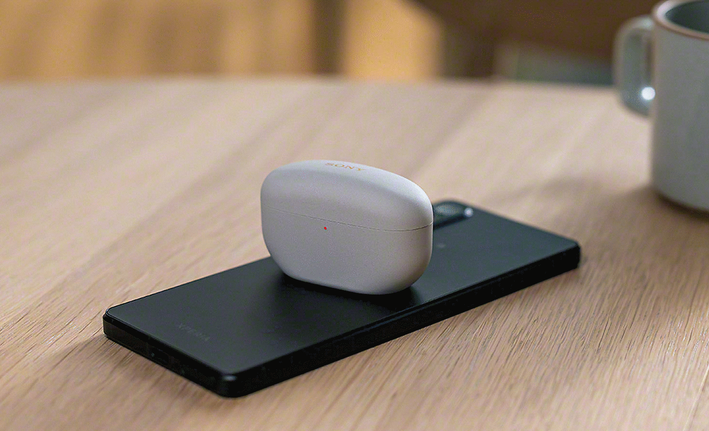 Snímek sluchátek do uší Sony uložených v pouzdře položeném na zadní straně smartphonu Xperia