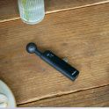 Photo of Black ECM-AX10 microphone on a wooden table beside a smartphone, coffee cup, notebook, and ribbed glass vase.