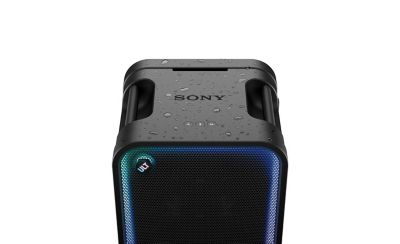En la imagen proporcionada, hay un parlante de SONY, identificado como el ULT TOWER MAX, destacado en primer plano. En el fondo, hay un grupo de personas bailando en lo que parece ser una fiesta nocturna o una reunión al aire libre. También hay una pequeña etiqueta "FPO" (solo para fines de maquetación) en la esquina superior derecha.