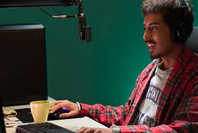 Image montrant un homme assis devant l'écran d'un PC et portant un casque relié par un câble à un microphone