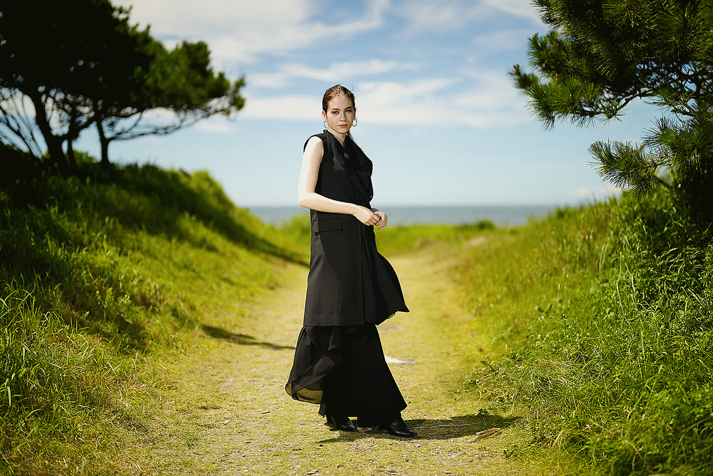 Image of a woman with beautiful bokeh, standing in a path to a beach
