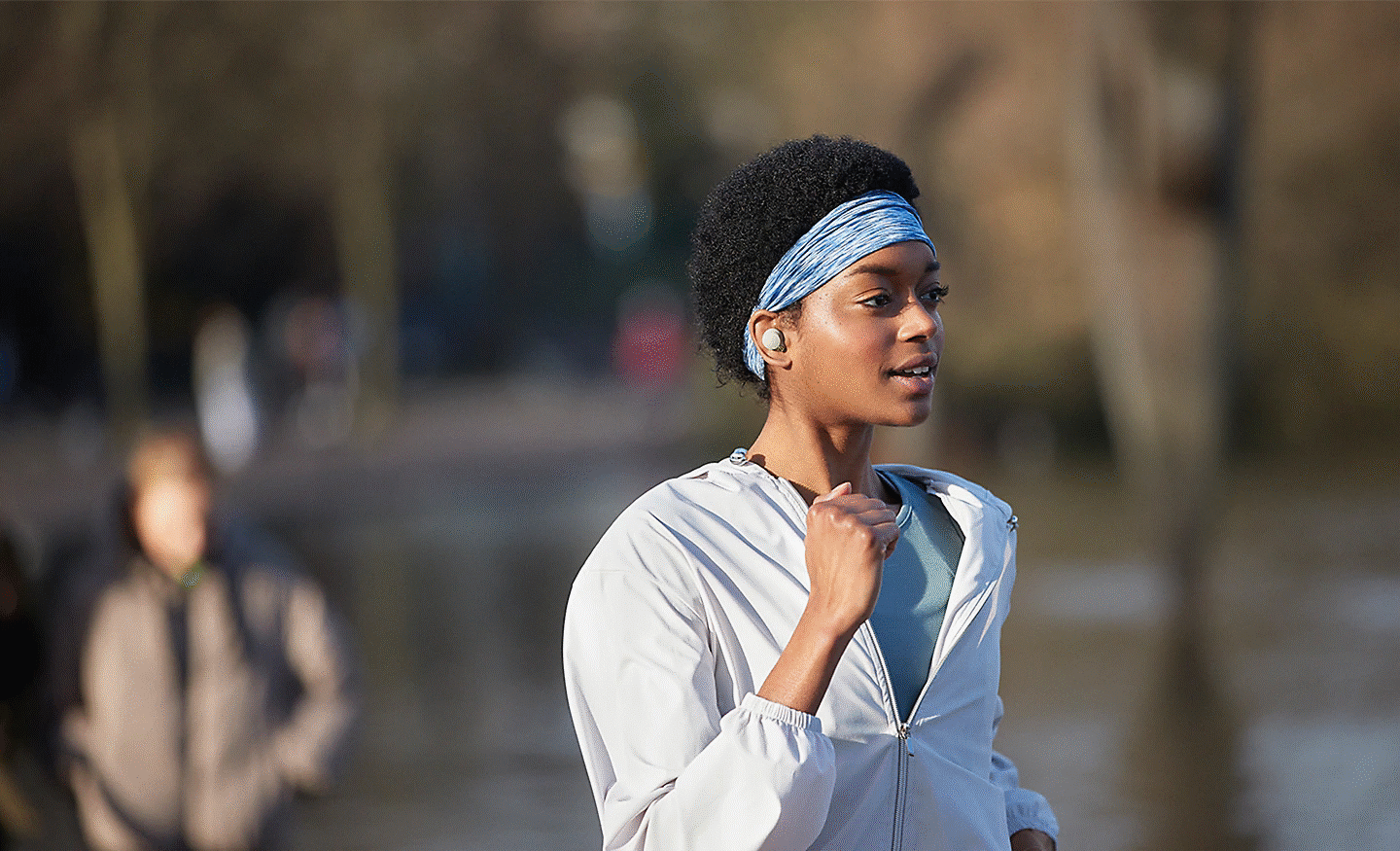 A woman running outdoors wearing WF-1000XM4 headphones