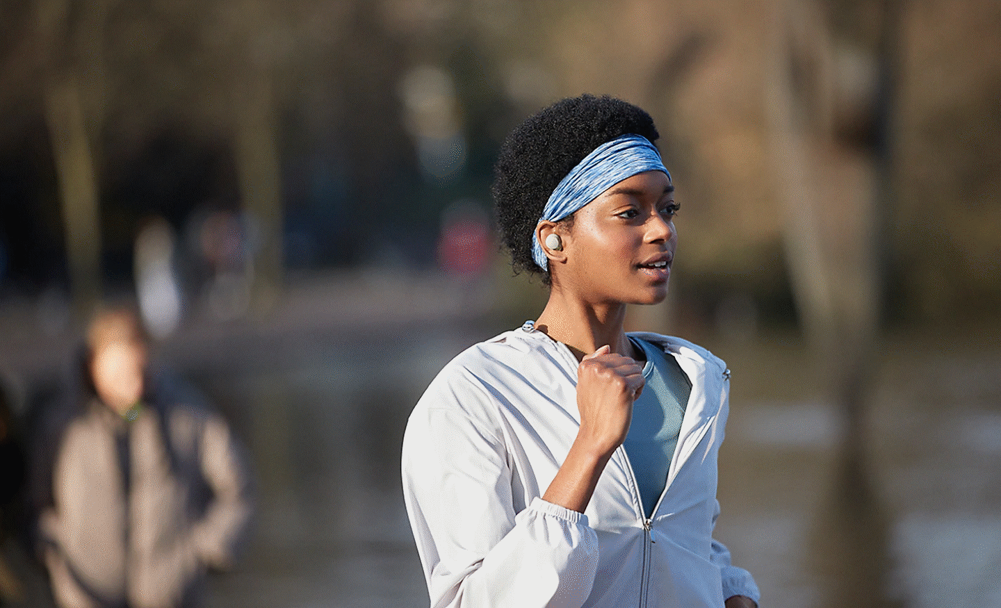 A woman running outdoors wearing WF-1000XM4 headphones