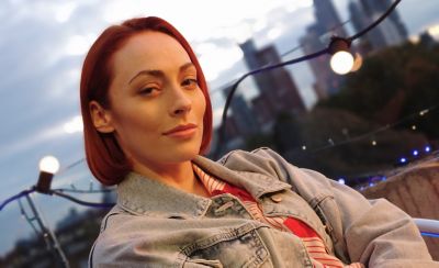 A person on a rooftop stood in front of a string of fairy lights with a city skyline in the background 