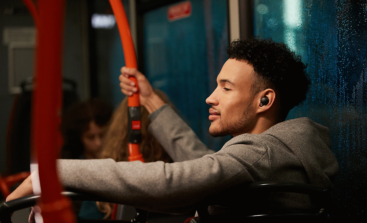 Mand med WF-1000XM4-hovedtelefoner på i en bus om aftenen