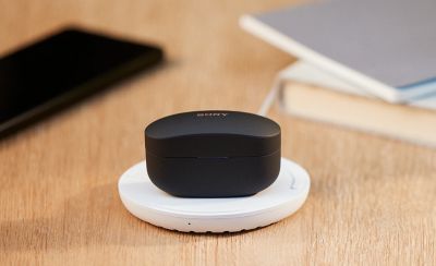 Työpöydällä olevia esineitä, mukaan lukien WF-1000XM4-latauskotelo langattomalla latausalustalla.