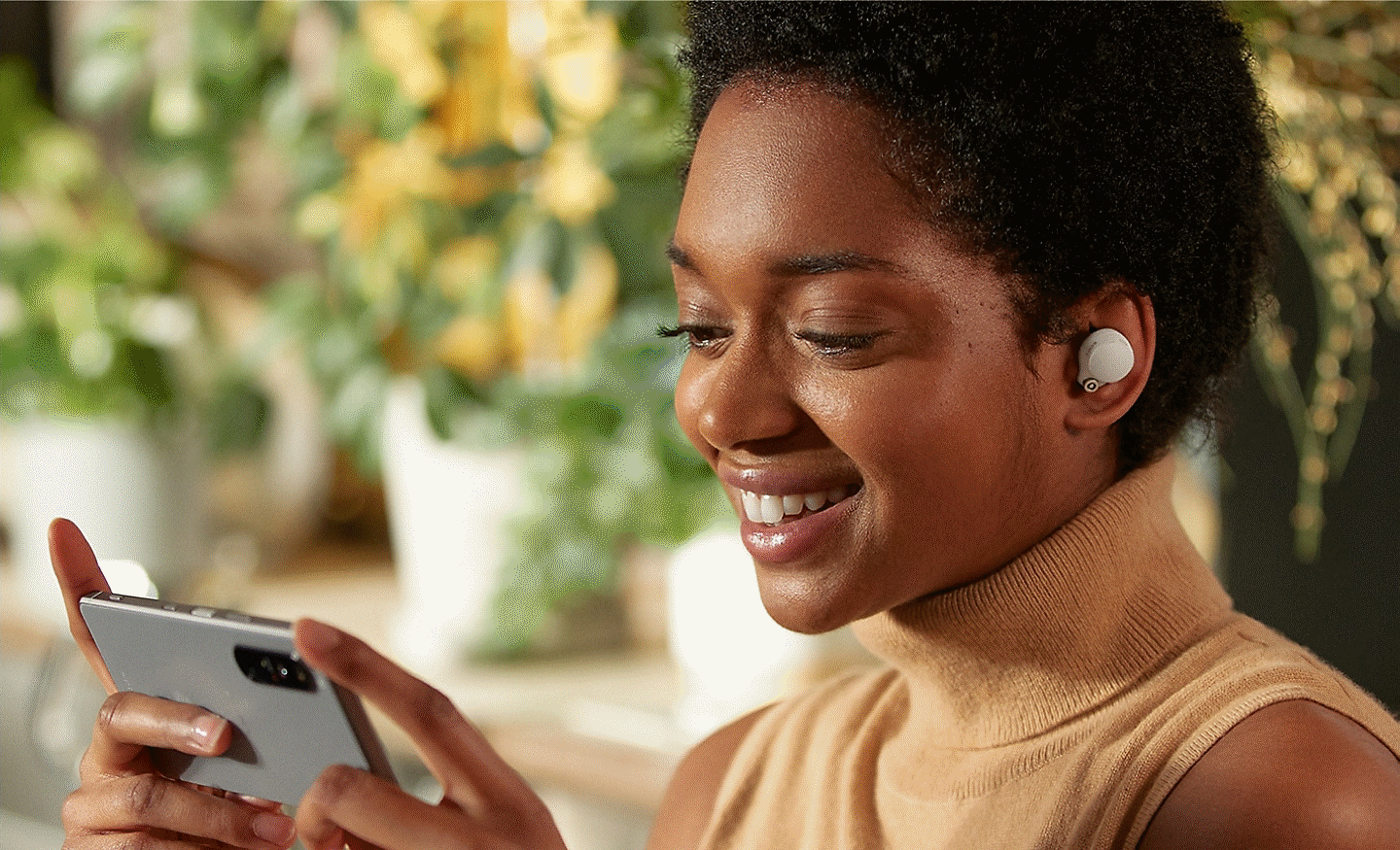 Mulher a utilizar os auriculares WF-1000XM4 e a ver conteúdos no seu smartphone
