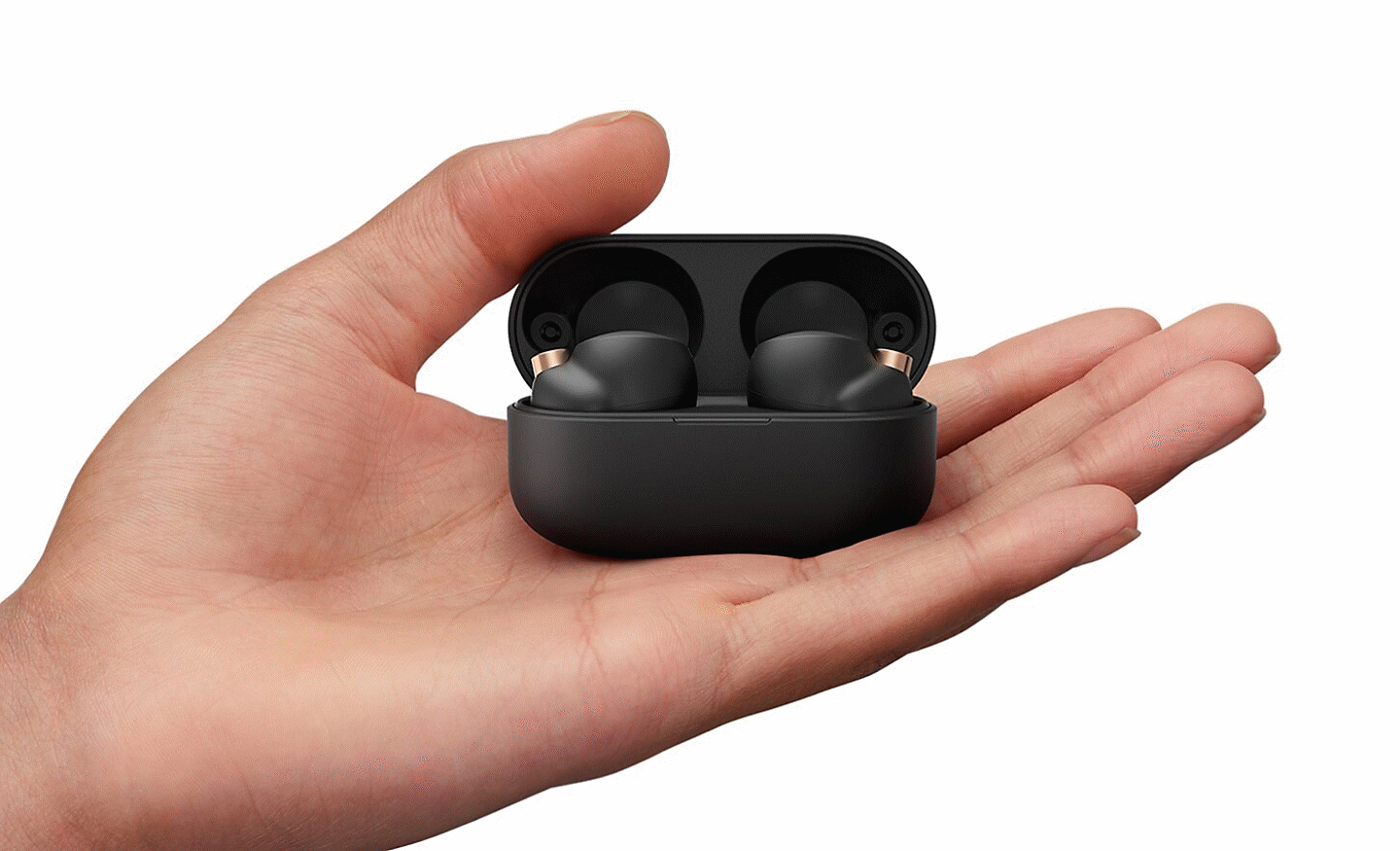 Hand holding an open charging case revealing the WF-1000XM4 headphones inside
