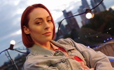 A person on a rooftop stood in front of a string of fairy lights with a city skyline in the background 