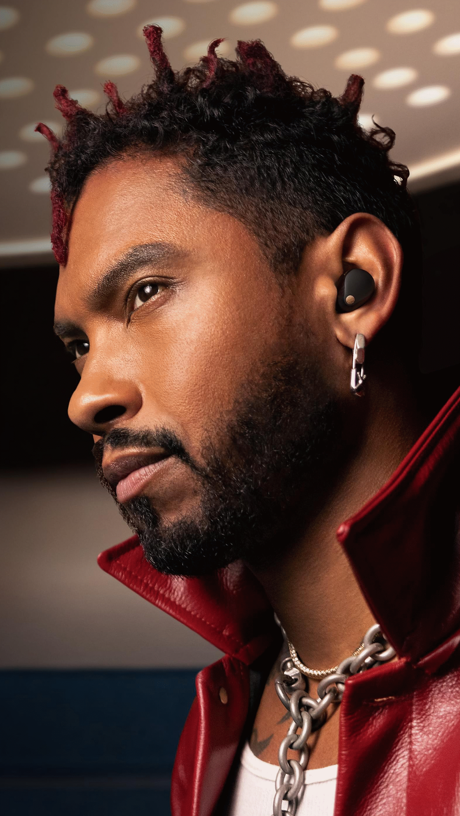Image of Miguel wearing black WF-1000XM5 headphones with futuristic lighting in the background