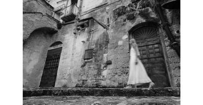 Image of a woman walking past a stone building in BW (Black & White) mode