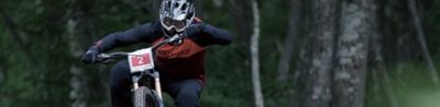 Example image of competition motorcycle rider in motion, in focus against woodland in background bokeh