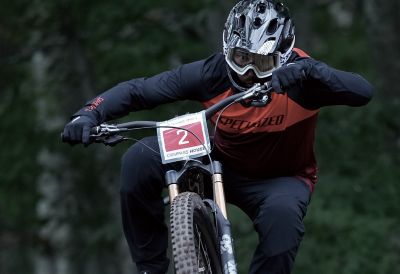 Example image of competition motorcycle rider in motion, in focus against woodland in background bokeh