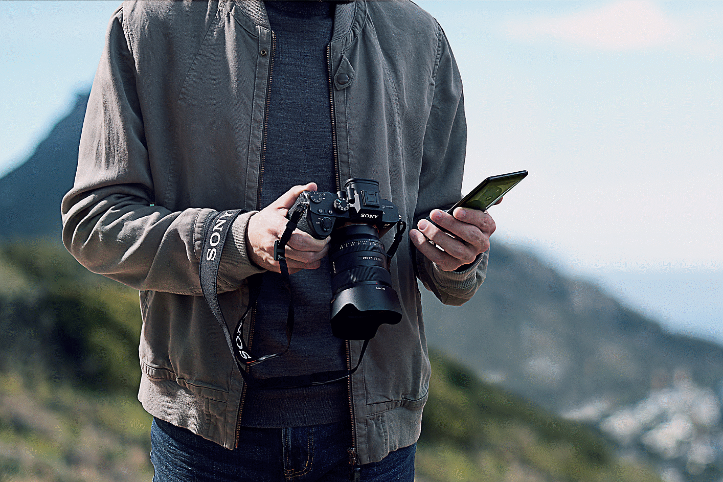Image d'un homme tenant l'appareil photo α1 et un smartphone