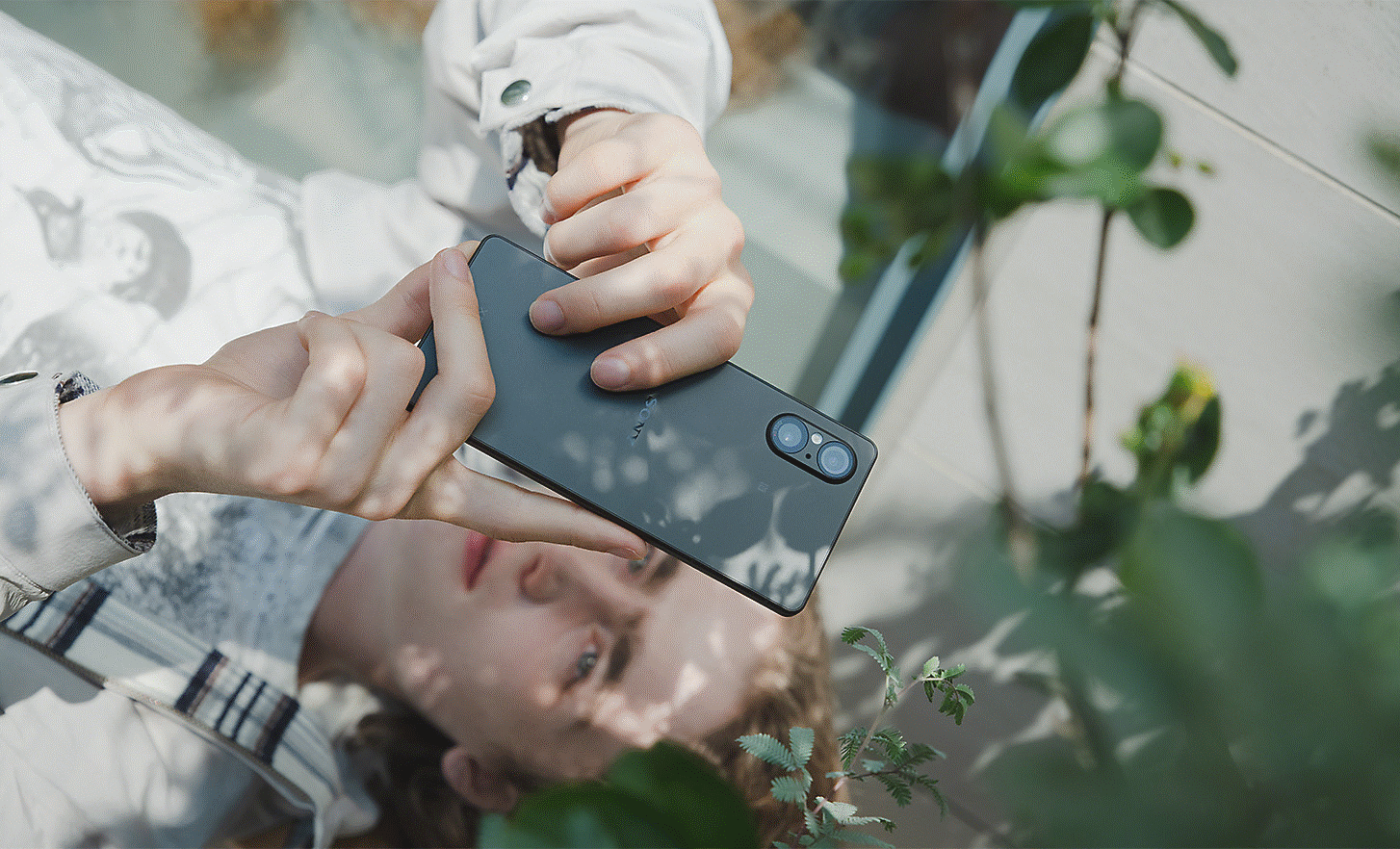 Image of a person taking a close up photo of a branch using a black Xperia 5 V