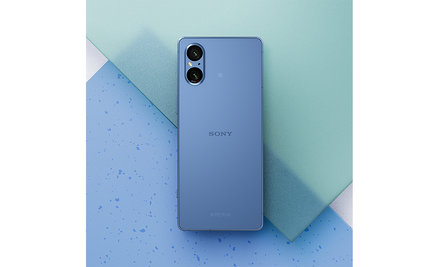 Image of a blue Xperia 5 V sitting on a sheet of glass and blue granite