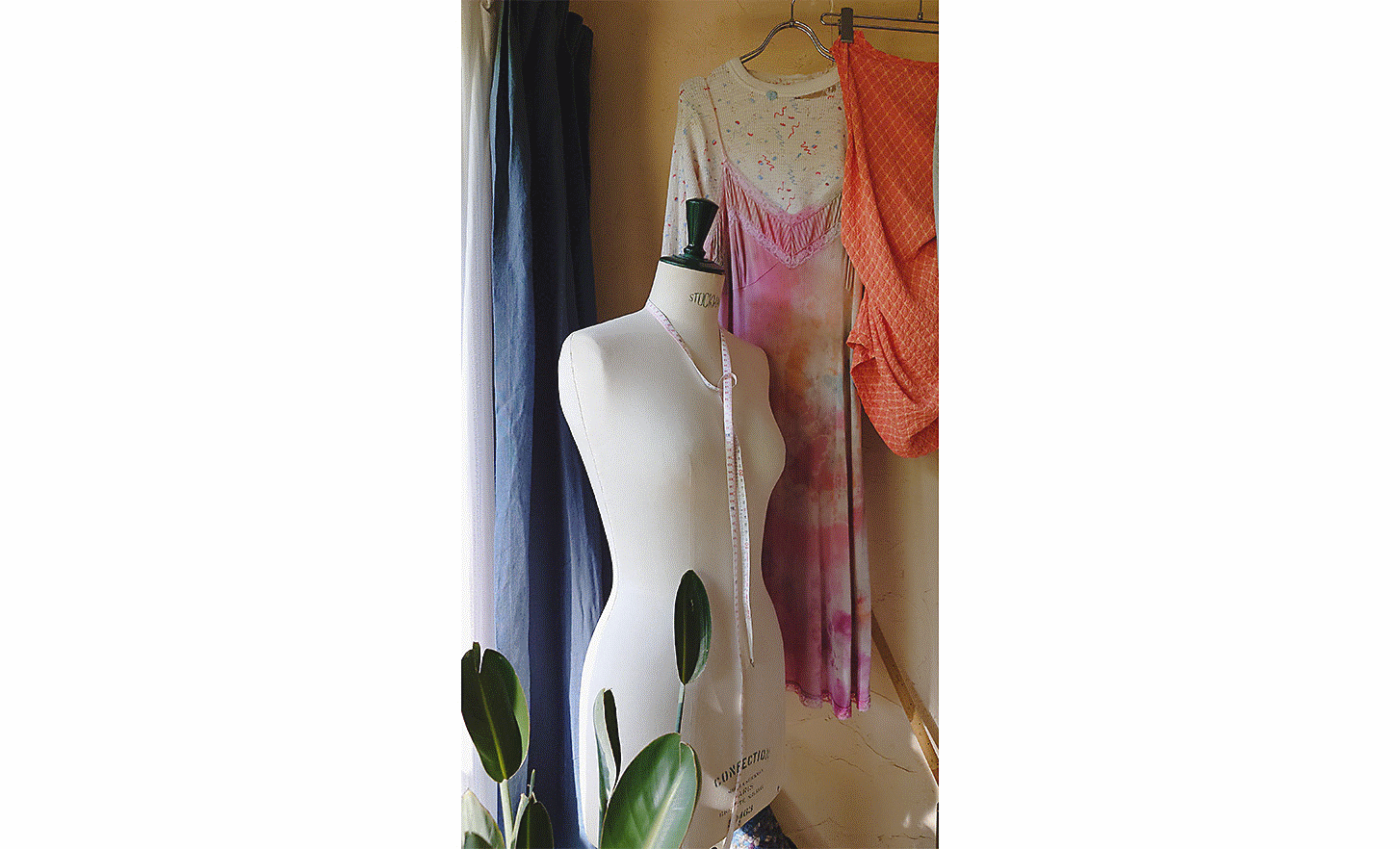 Image d'un mannequin avec un mètre-ruban autour du cou et une sélection de vêtements suspendus à côté